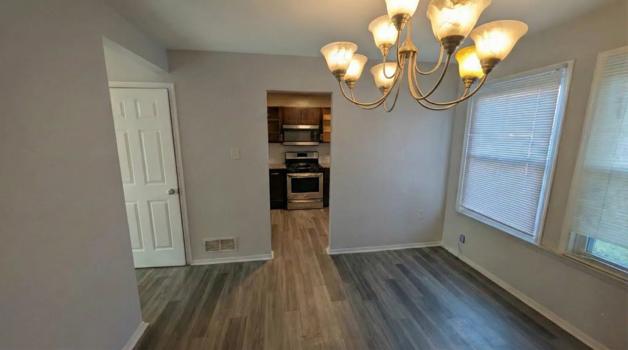 Townhome dining room with hanging lights and two large windows with closed blinds.