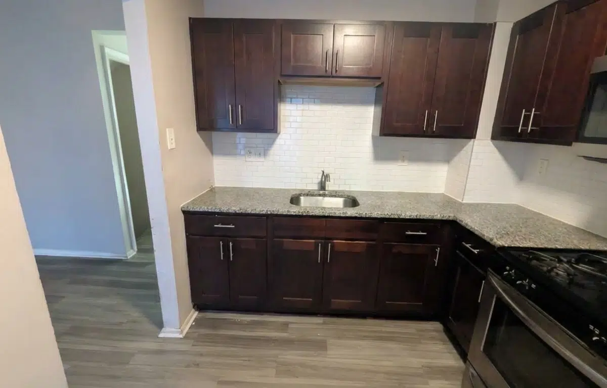 Beautiful kitchen with wood cabinets, granite counters a stainless steel sink and a black stainless steel oven.