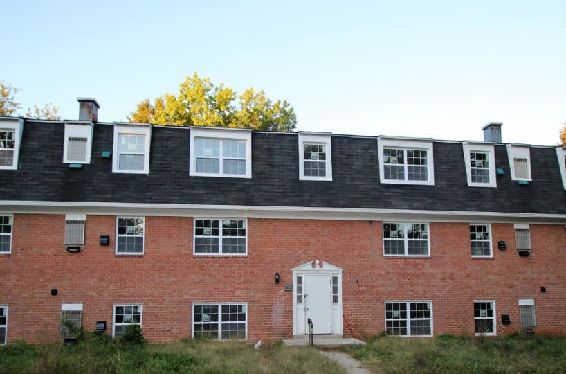 Red brick apartment building with white framed windows and white front door.