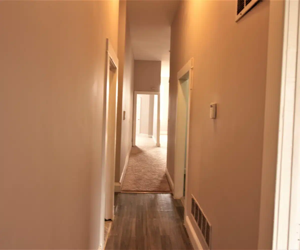 Partially carpeted hallway with doorways.
