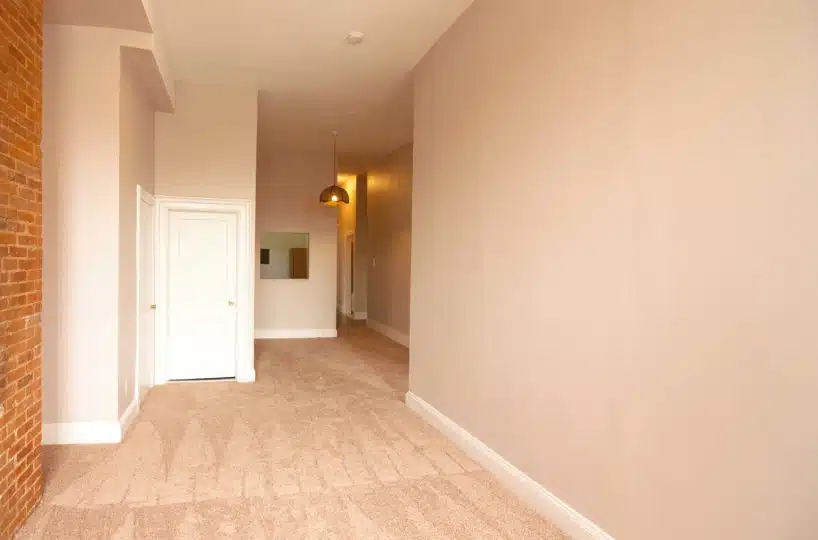 Carpeted living room with red brick wall and hanging light fixture.