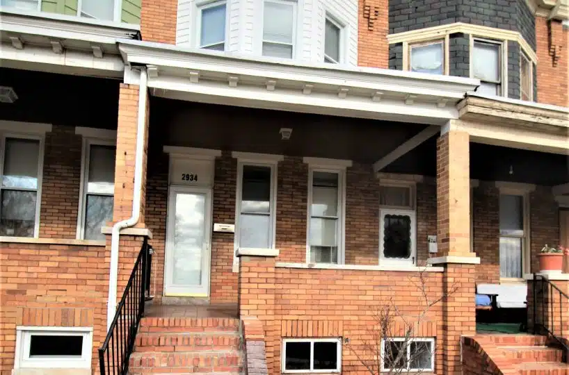 Brick townhome with red brick porch and black metal railing.