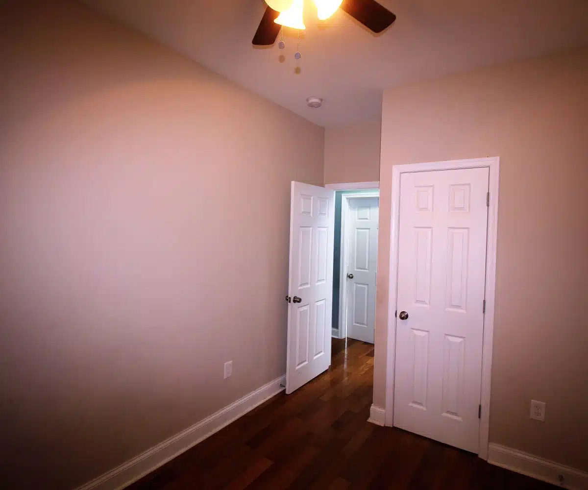 Pink bedroom with white doors and ceiling fan.
