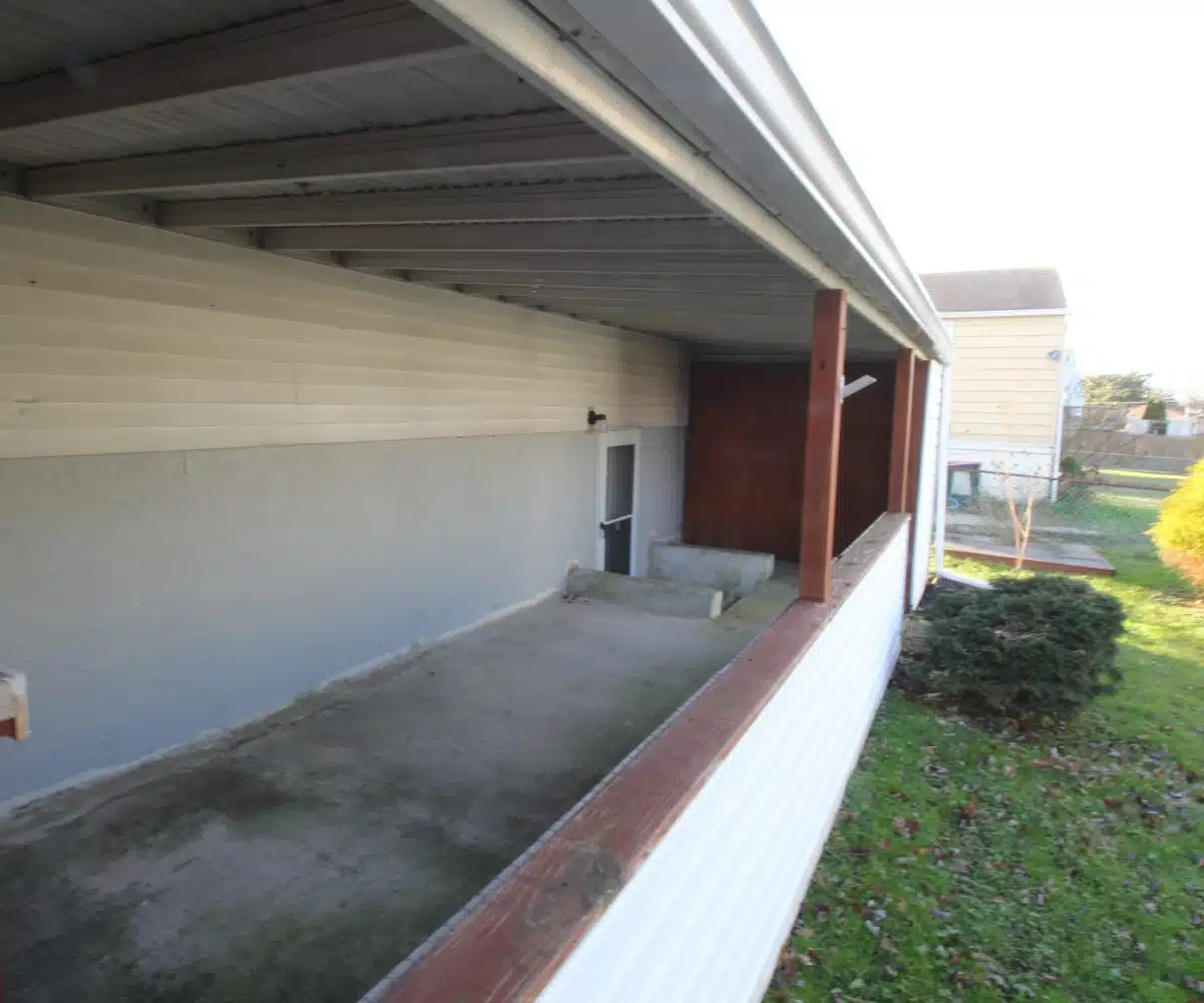 Covered back porch with grey concrete flooring and back door.