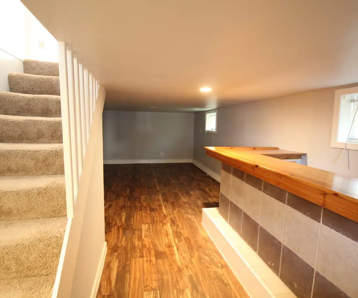 Basement with wood floor, recessed ceiling light, two windows, and wood counter.