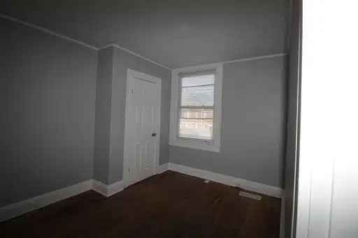 Room with grey walls, window and wood flooring.