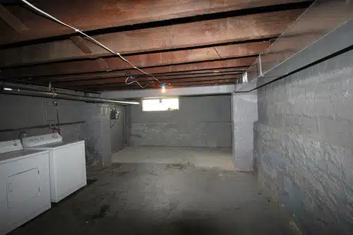 Basement with brick walls, wood rafters, and a washer and dryer.