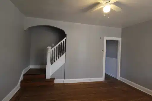 Living room with wood stairs, white railing and grey walls.