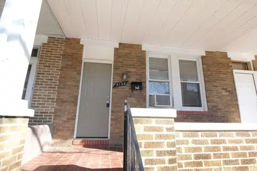 Brick front porch with two windows and grey front door.