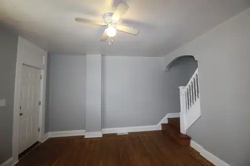 Living room with wood flooring, grey walls, ceiling fan and stucco ceiling design.