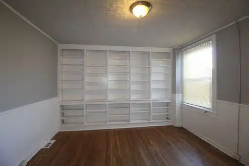 Grey and white living room with wood flooring and built-in shelving.