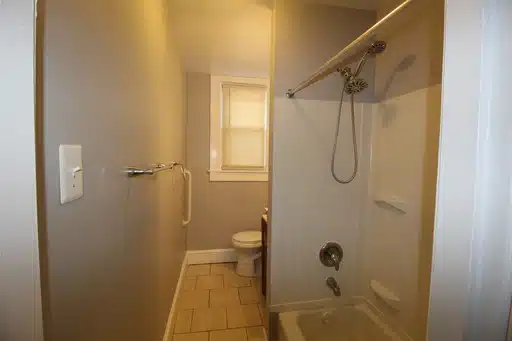 Bathroom with window, towel rack, toilet and bathtub.