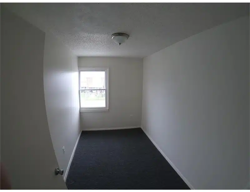 Room with window, stucco ceiling and blue carpeting.