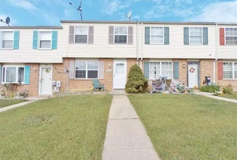 Rowhomes with green lawns, concrete paths and white front doors.