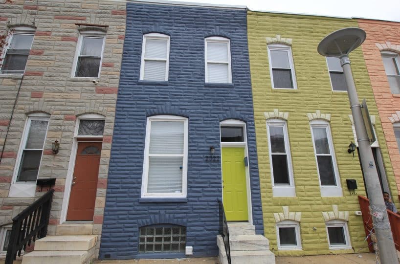Blue brick townhome with marble steps leading to green front door.