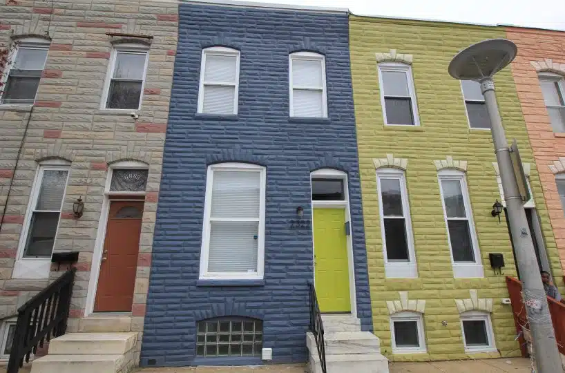 Blue brick townhome with marble steps leading to green front door.