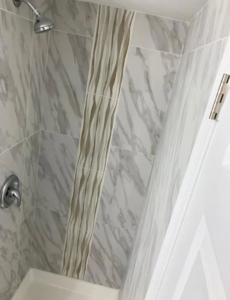 Shower with large wall tiles, silver showerhead and silver knob.
