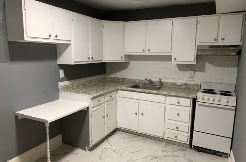 Kitchen with granite countertops, stainless steel sink and white stove.