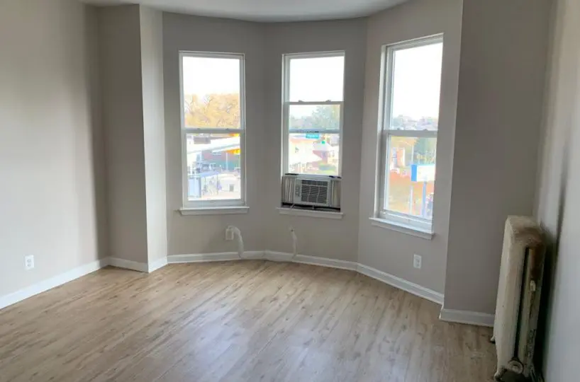 Living room with beige walls, white radiator, and three bay windows.