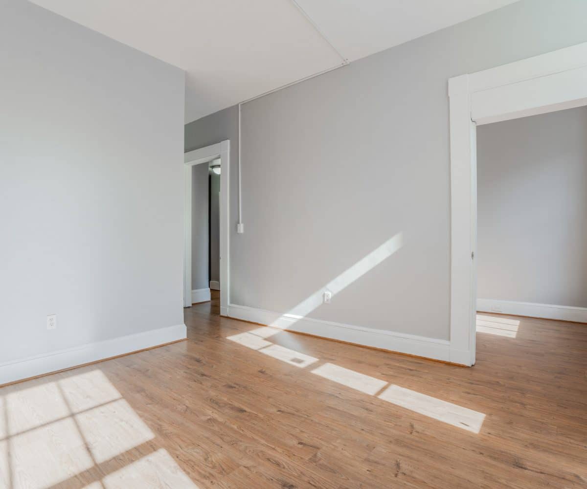 Grey walled living room with sunshine reflecting off of the hardwood floor.