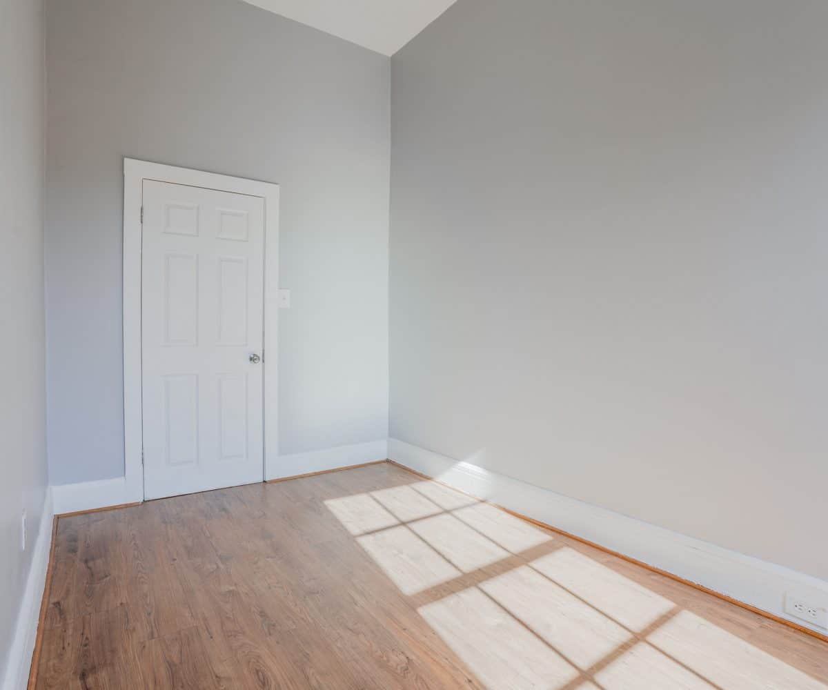 Grey walled bedroom with hardwood floor.