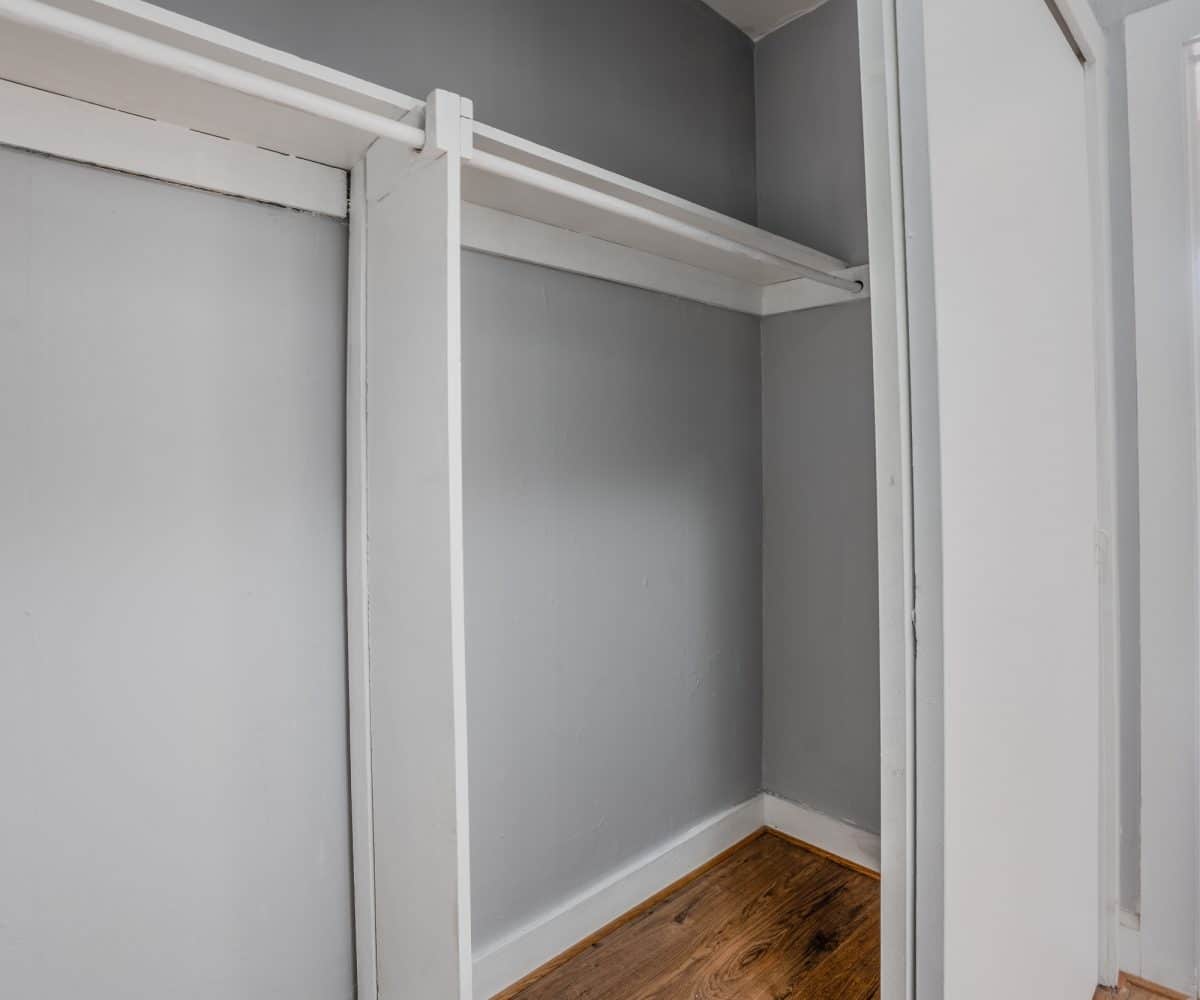 Large grey closet with hardwood floor.