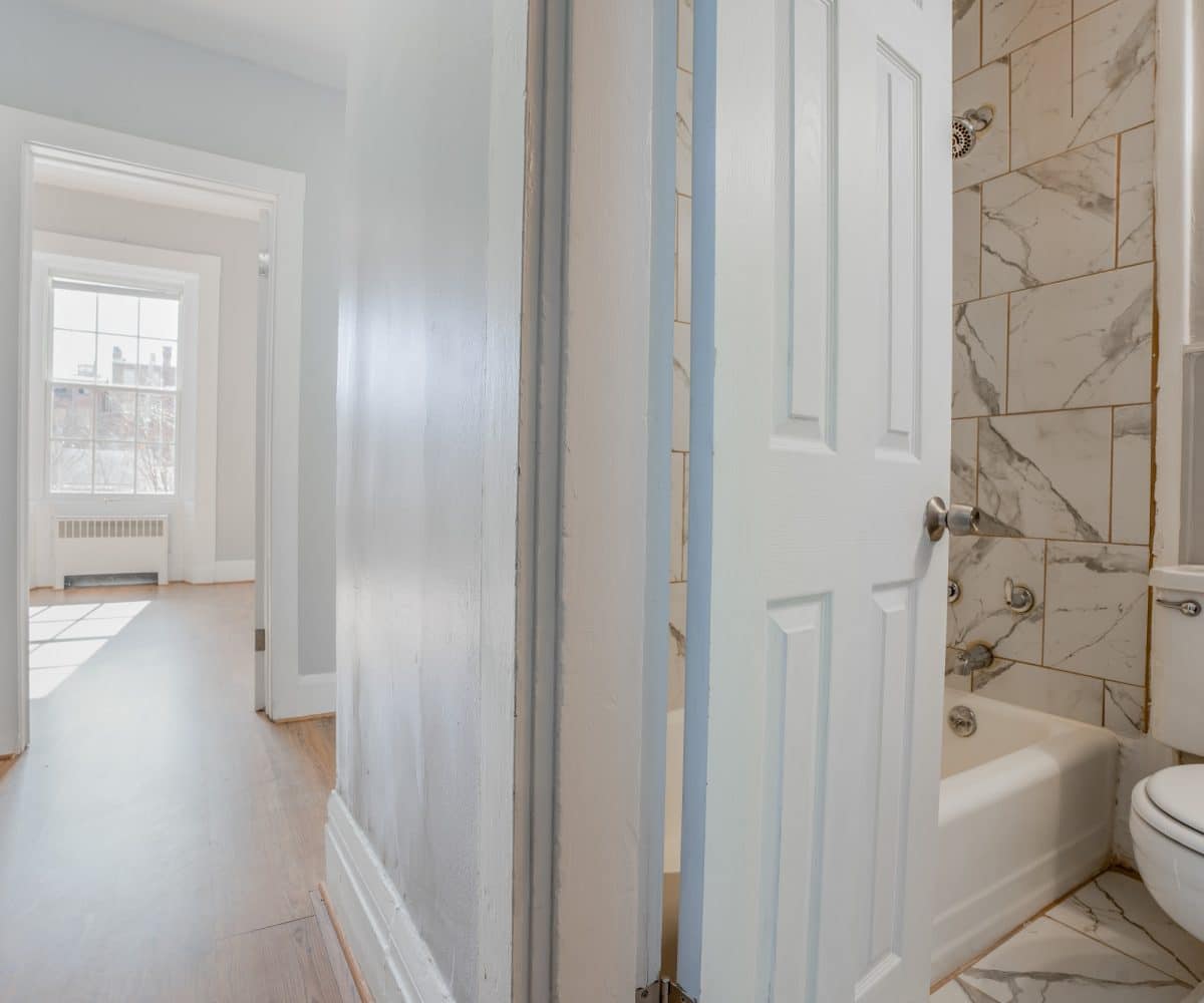 Hallway and bathroom with toilet and bathtub.
