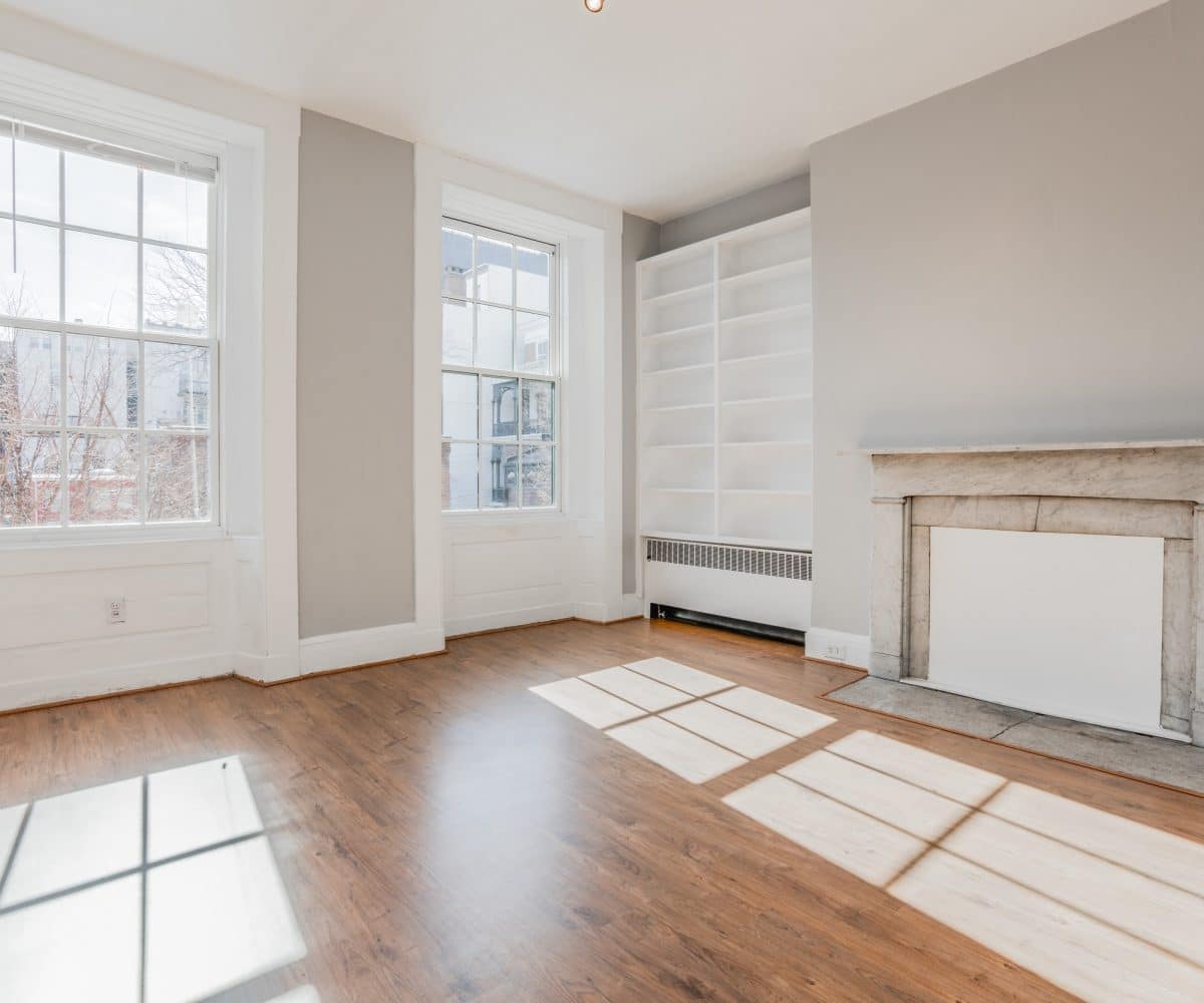 Sunny living room with two large indows, fireplace and bookcase.