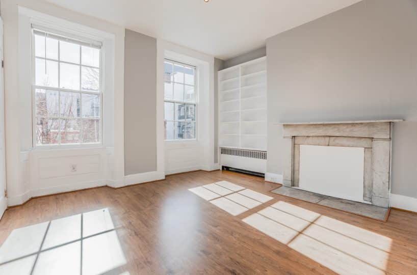 Sunny living room with two large indows, fireplace and bookcase.