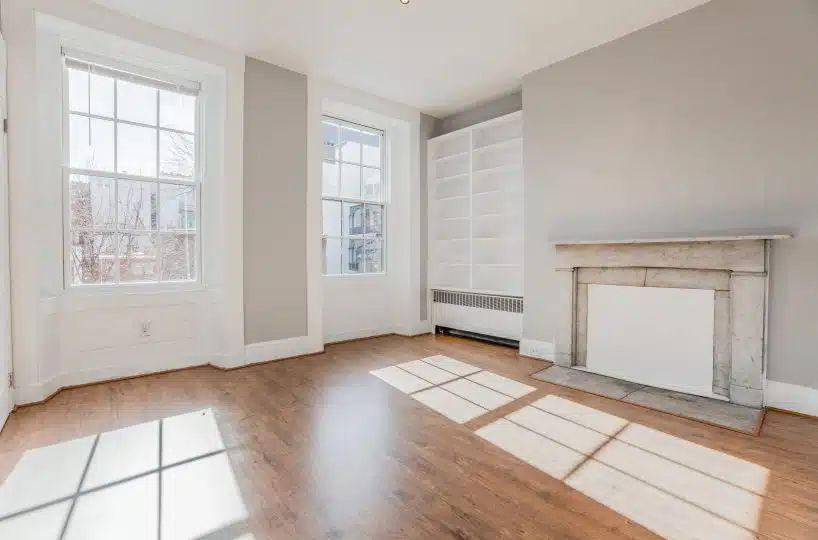 Sunny living room with two large indows, fireplace and bookcase.