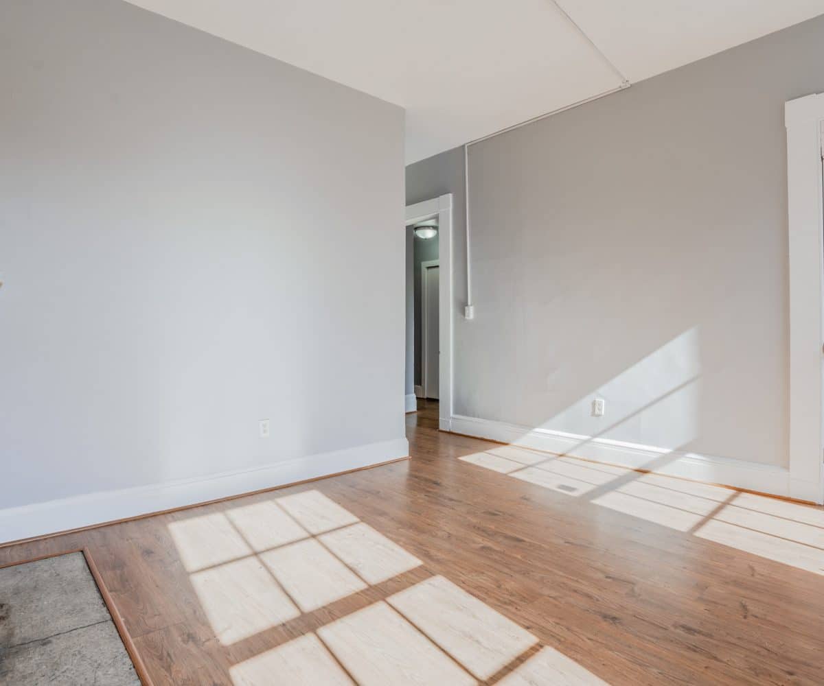Living room with grey walls, hardwood floors and grey marble fireplace.