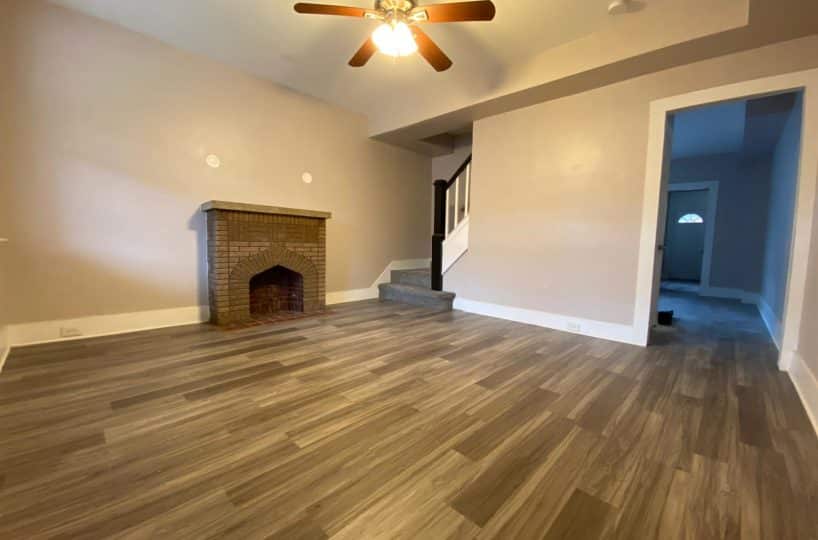 Living room with allure flooring, brick fireplace and ceiling fan.