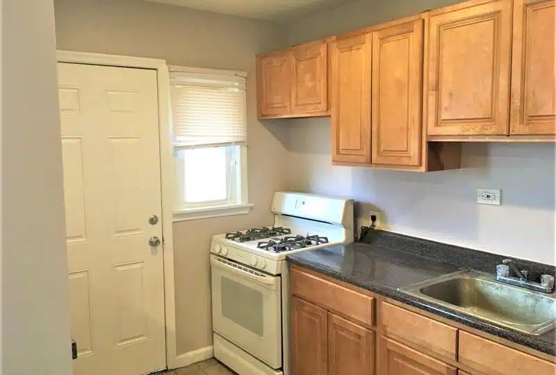 Kitchen with black countertops, white stove and window.