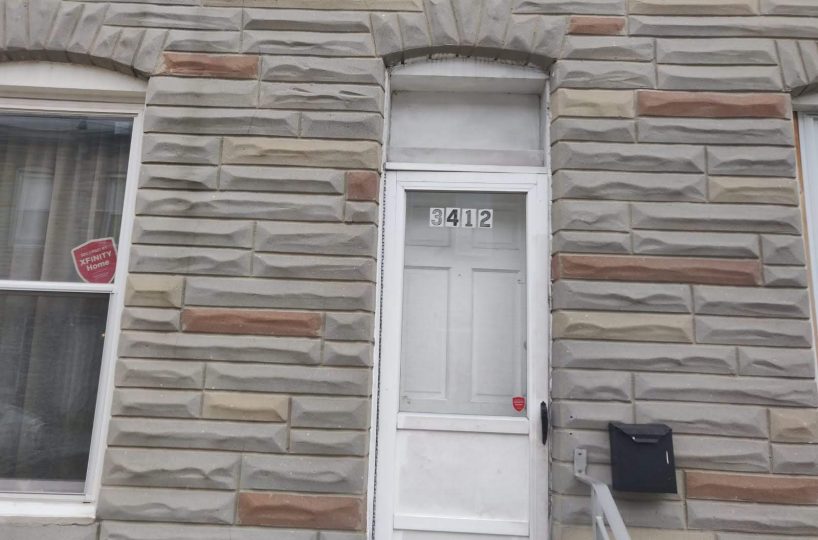 Brick townhome with white front door and black mail box.