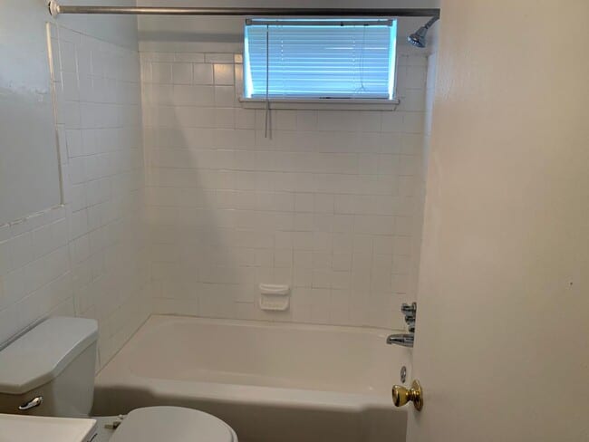 White bathroom with toilet and bathtub.