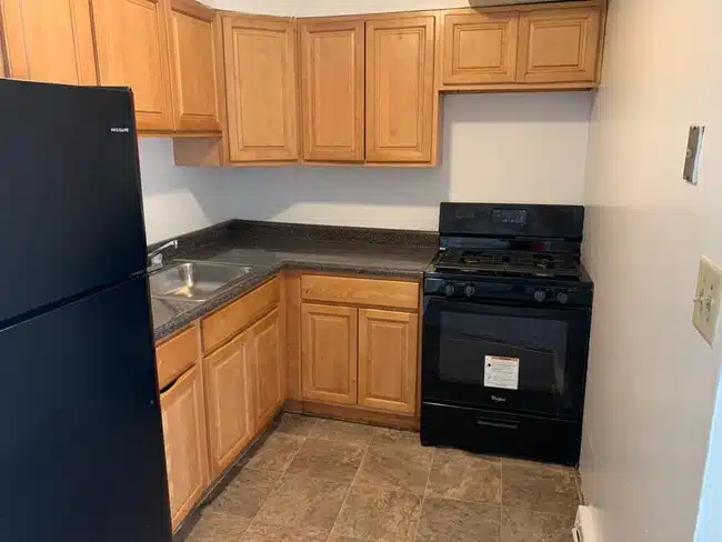 Kitchen with black fridge, wood cabinets and black oven.