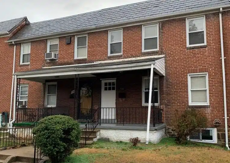 Brick townhome with grey porch and white front door.