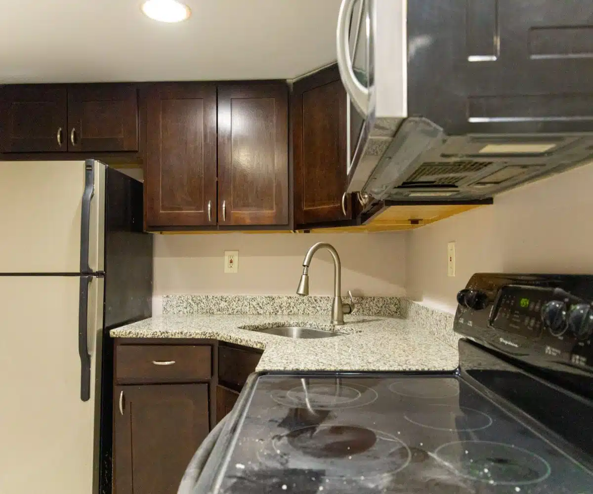 Kitchen with granite countertop, sink, fridge, stove, microwave and wood cabinets.