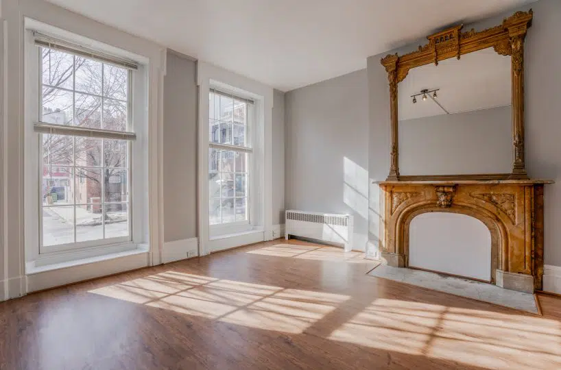 Living room with hardwood floors, marble fireplace and large mirror above it.