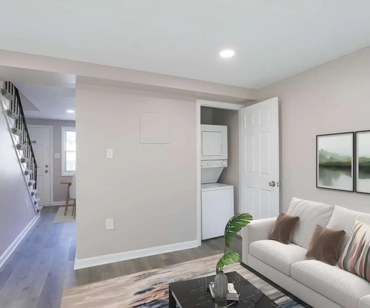 Living room with view of in-unit laundry, couch, rug and hallway.