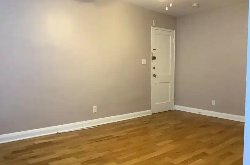 Living room with hardwood floors, grey walls and white front door.