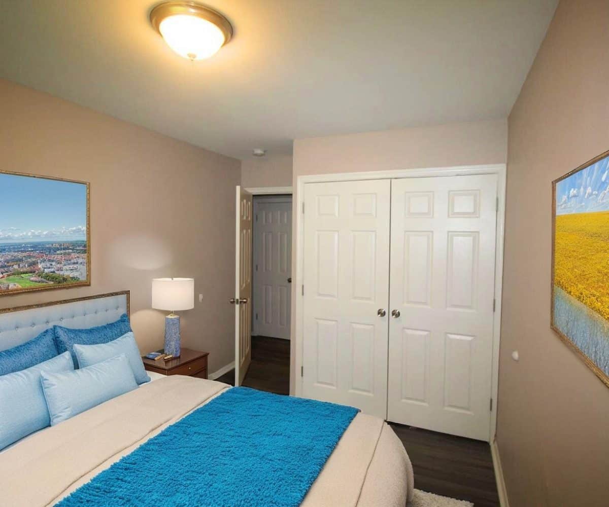 Bedroom with double bed, ceiling light and closet doors.