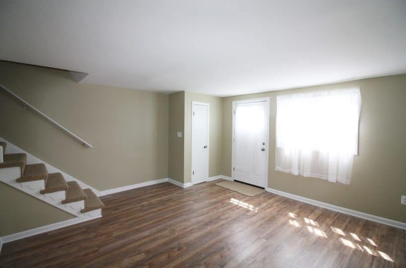 Living room with lime colored walls, hardwood floors and carpeted staircase.
