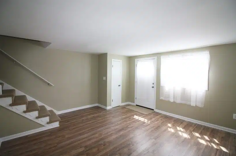 Living room with lime colored walls, hardwood floors and carpeted staircase.