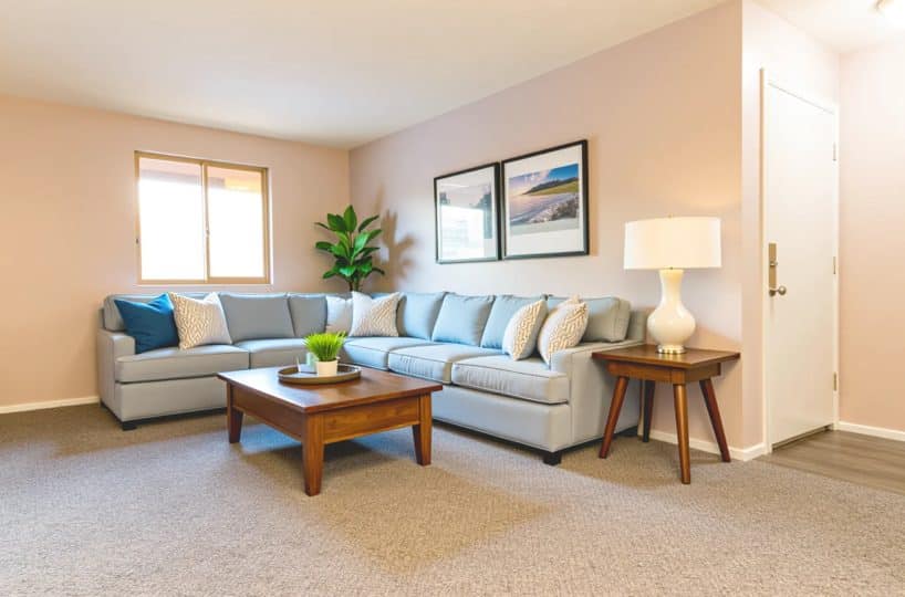 Living room with blue sofa, coffee table, white lamp, and grey carpeting.
