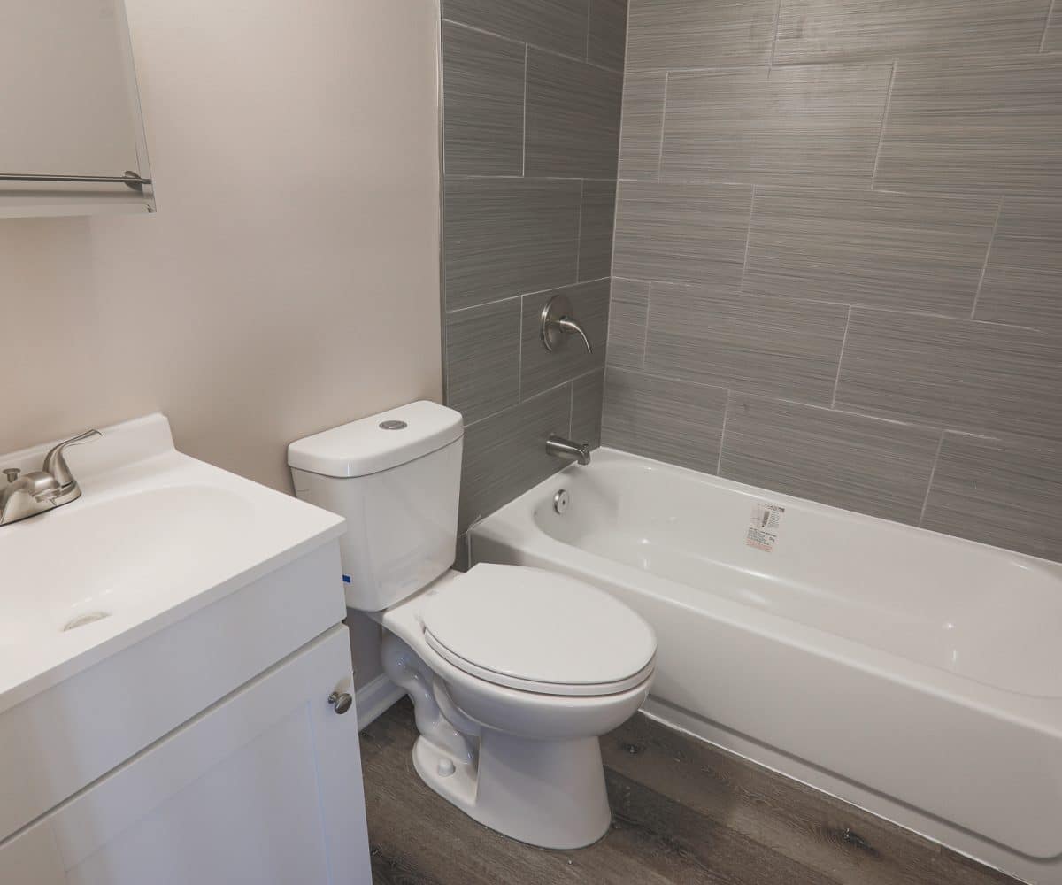 Bathroom with tiled bathtub, toilet, and sink.