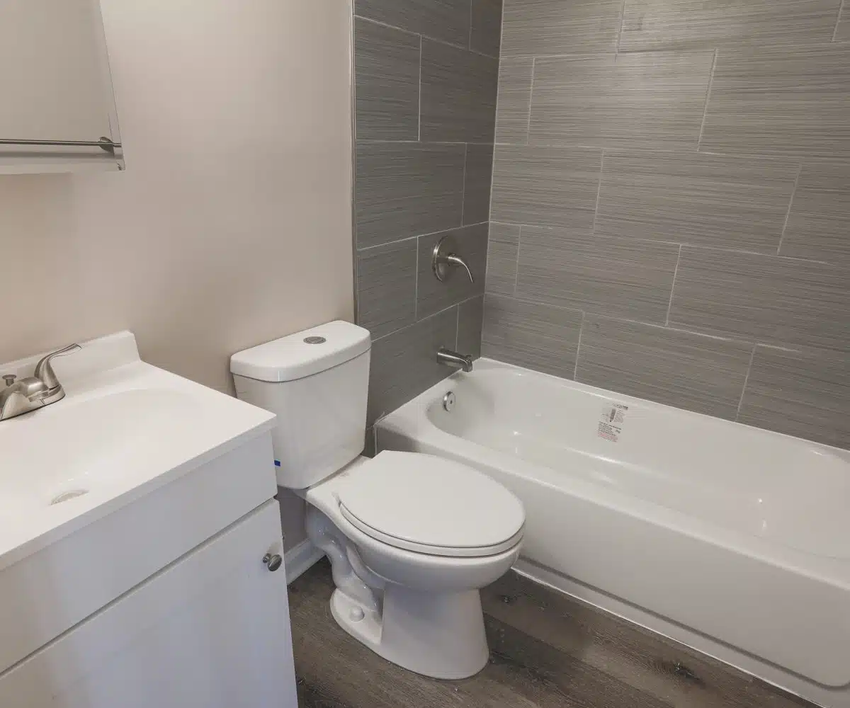 Bathroom with tiled bathtub, toilet, and sink.