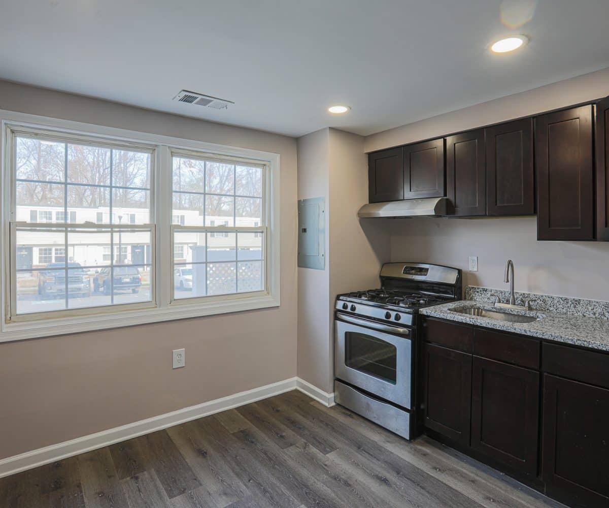 Kitchen with stove, sink, granite counters and wooden cabinets.