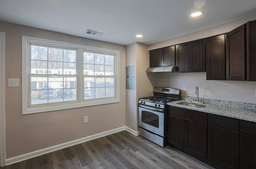 Kitchen with stove, sink, granite counters and wooden cabinets.