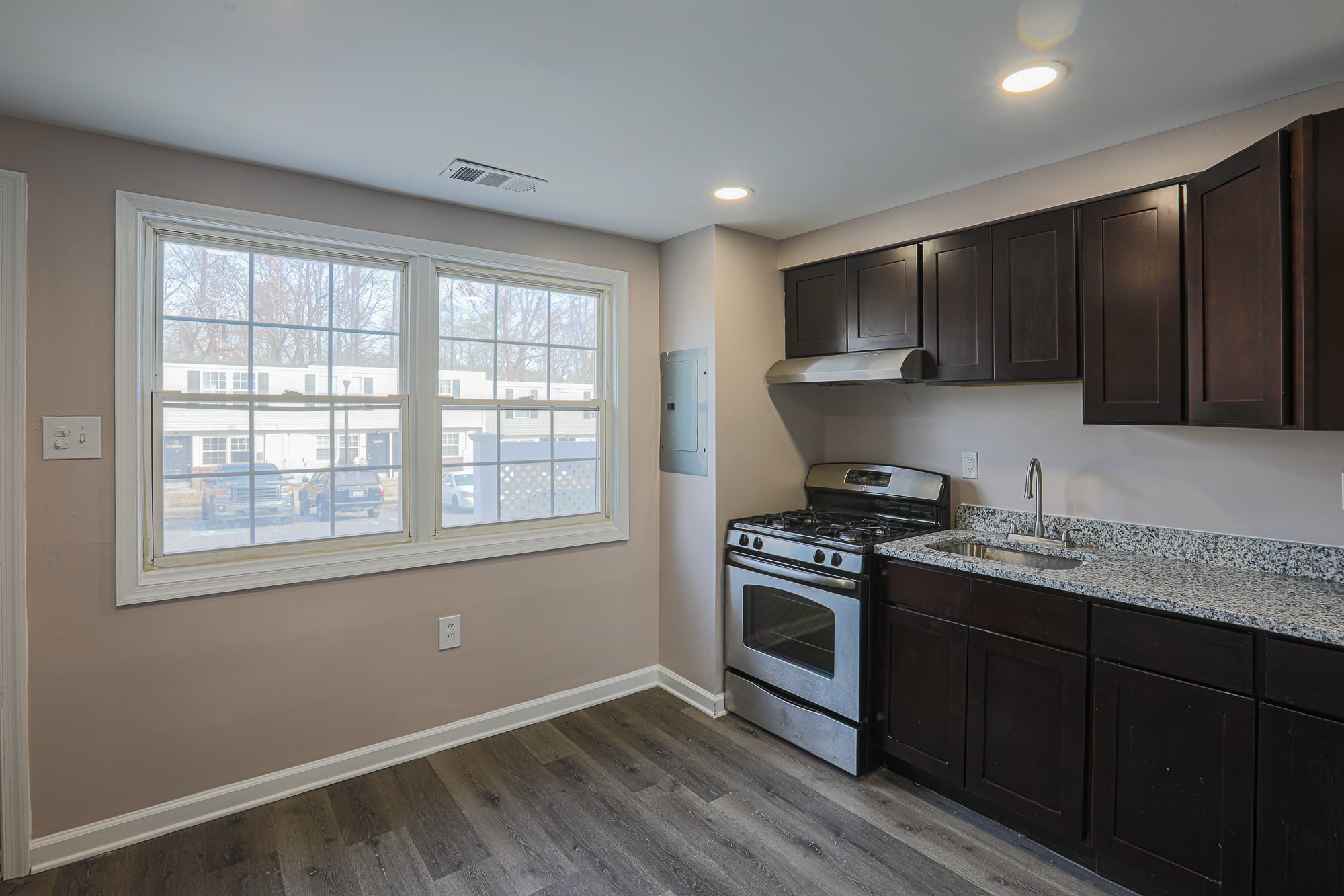 Kitchen with stove, sink, granite counters and wooden cabinets.